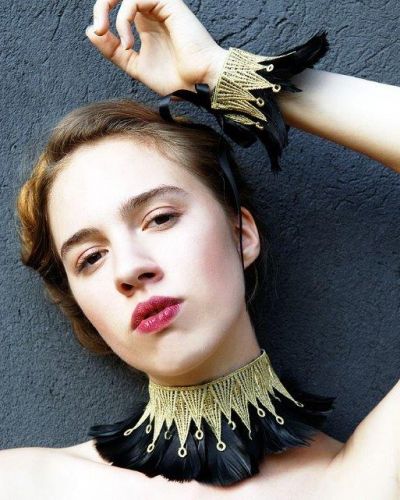 Model trägt handgefertigten Hals- und Armschmuck aus Federn und raffinierten Stickereien der Marke Mondin.