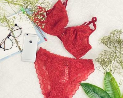 Rote Dessous liegen auf einem Tisch neben Handy und Brille.