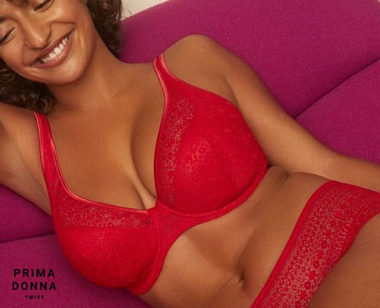 Model in roten Dessous liegt auf einer Couch.