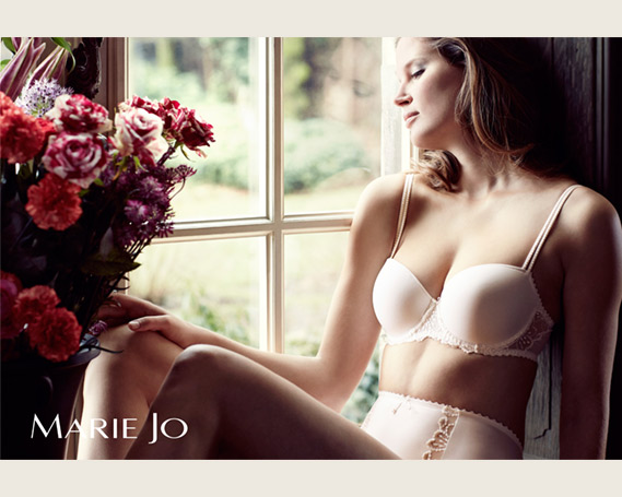 Model in Dessous der Marke Marie Jo sitzt am Fenster.